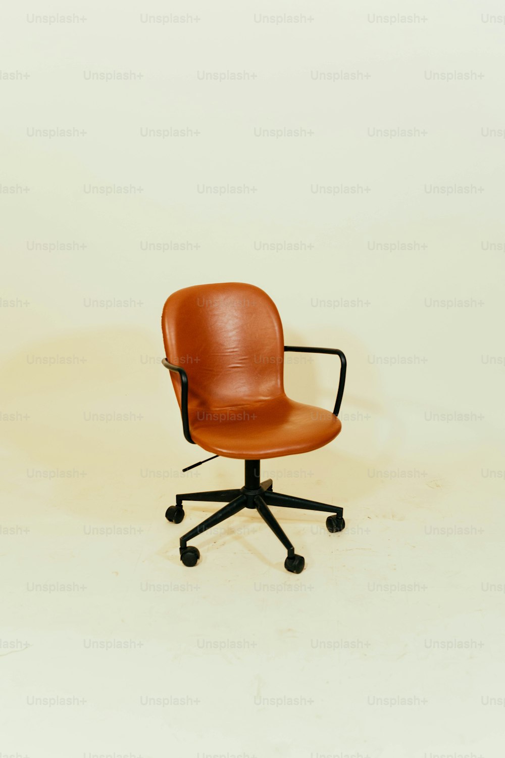 Una sedia da ufficio marrone seduta sopra un pavimento bianco