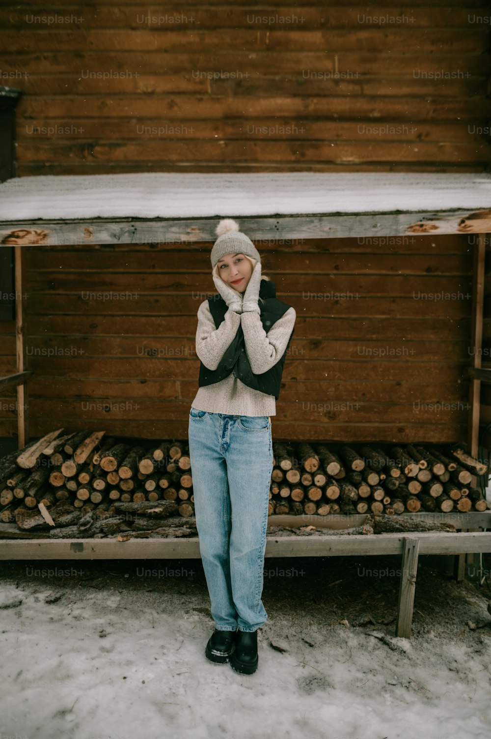 a woman standing in front of a pile of logs