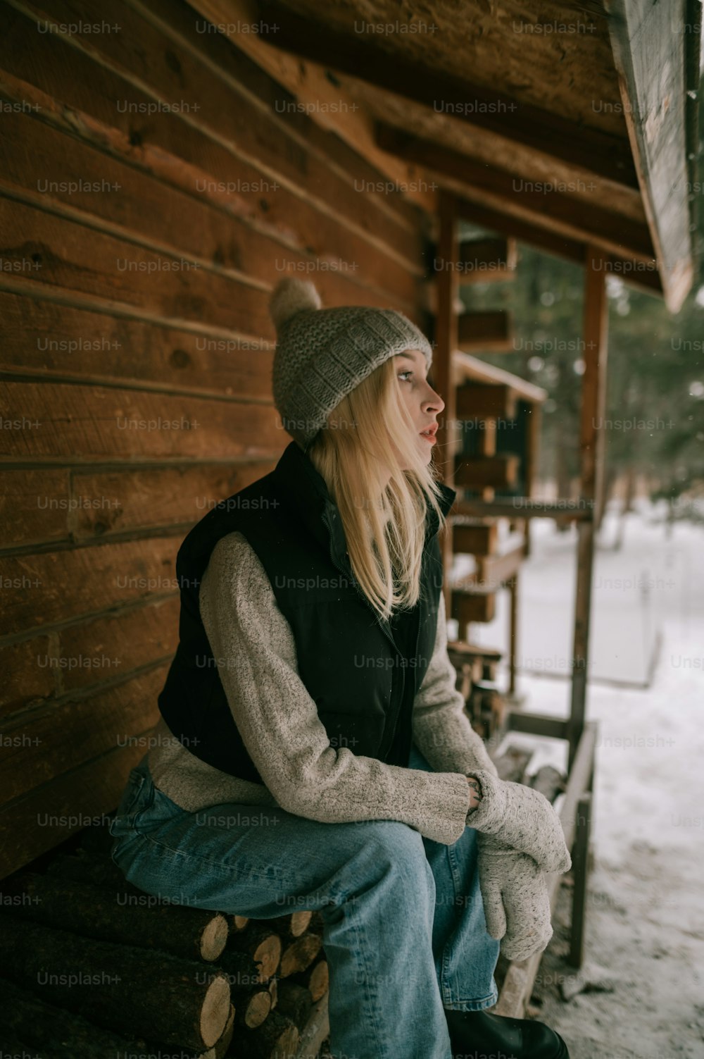 a woman sitting on a bench in front of a log cabin