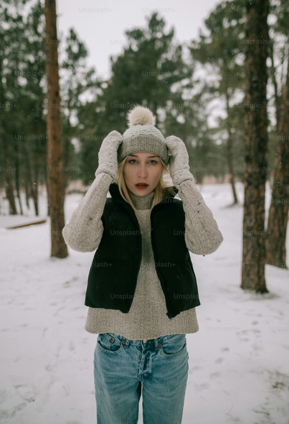 Eine Frau, die mit den Händen auf dem Kopf im Schnee steht