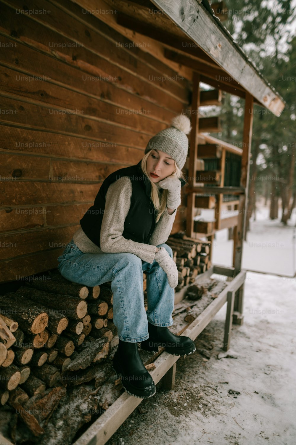 Una mujer sentada encima de una pila de troncos