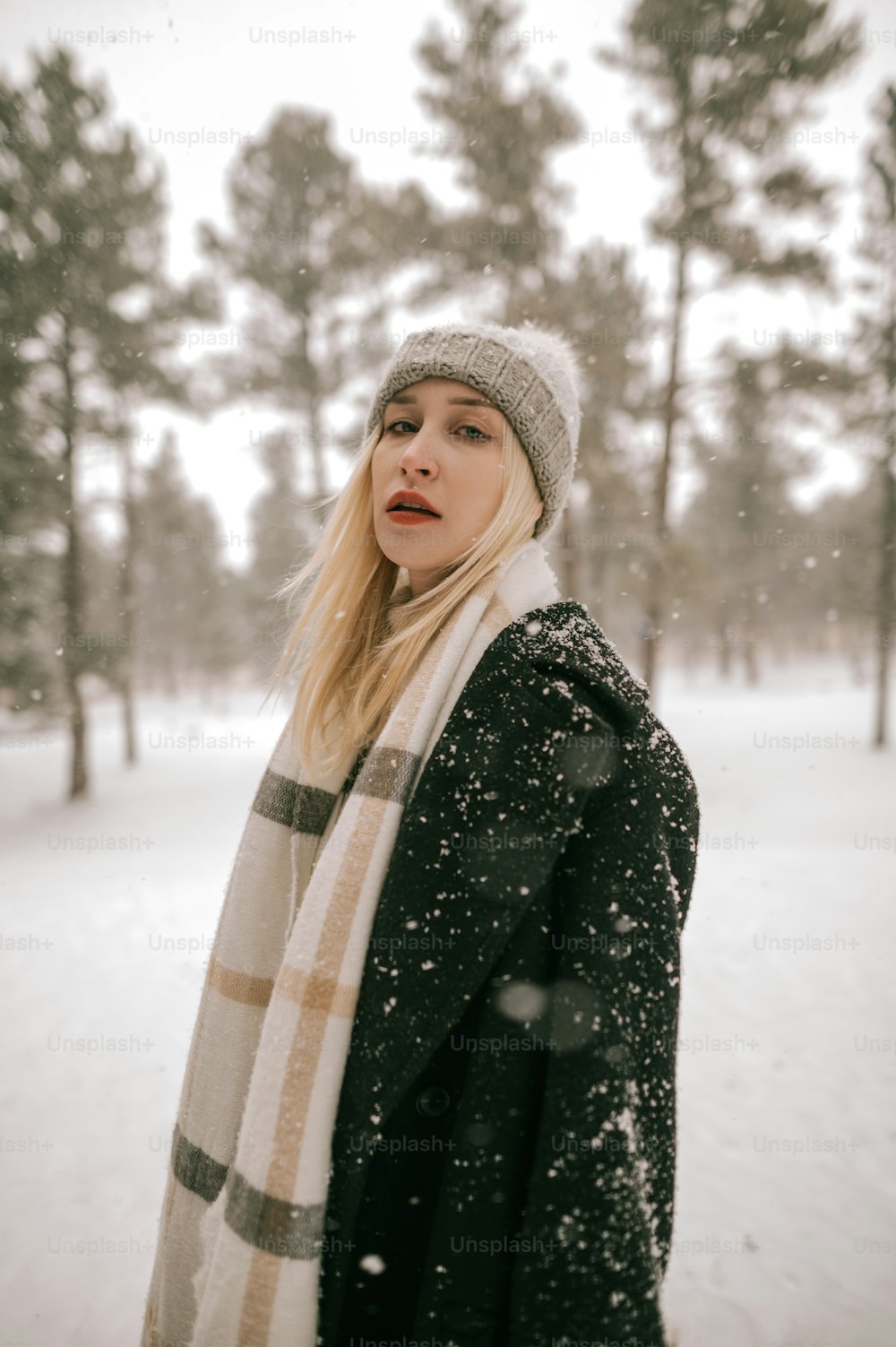 a woman standing in the snow with a scarf around her neck