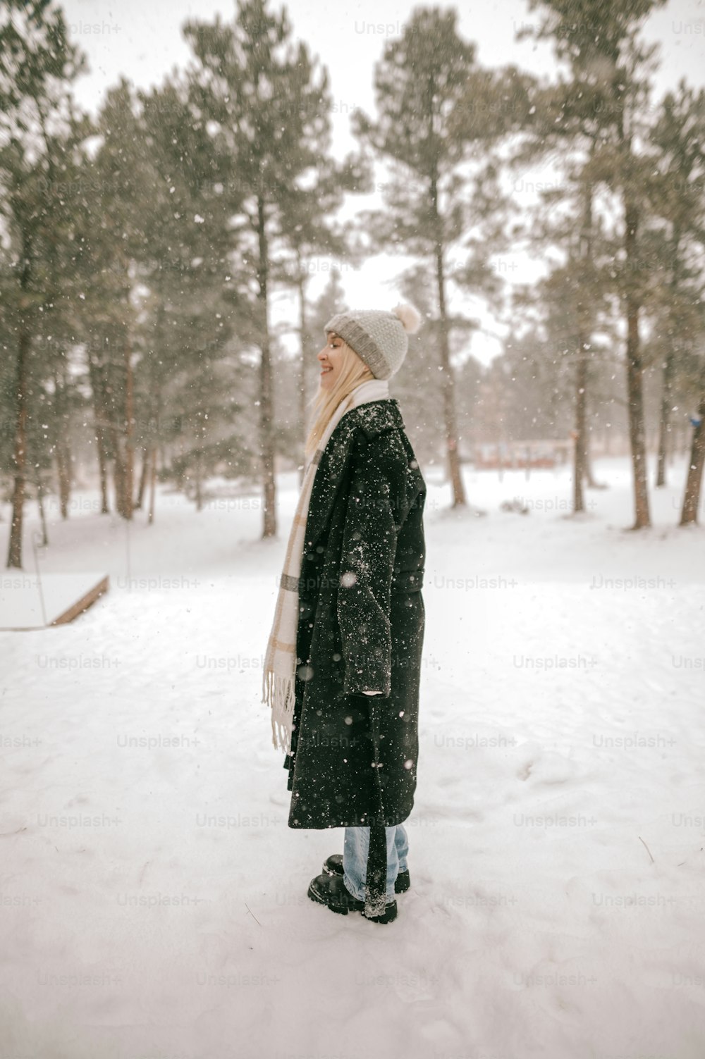 a woman standing in the snow wearing a coat and hat