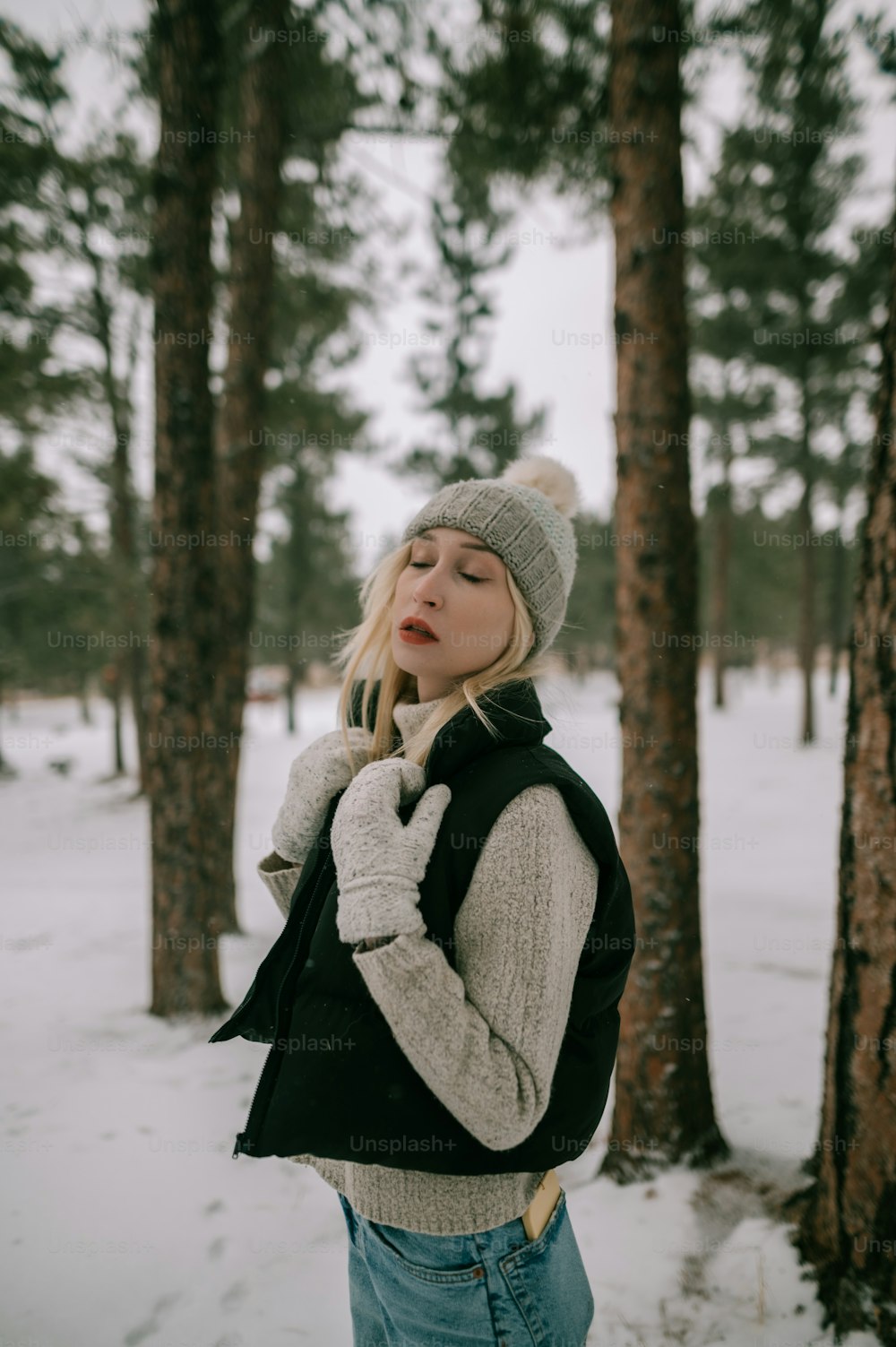 木々の前で雪の中に立つ女性