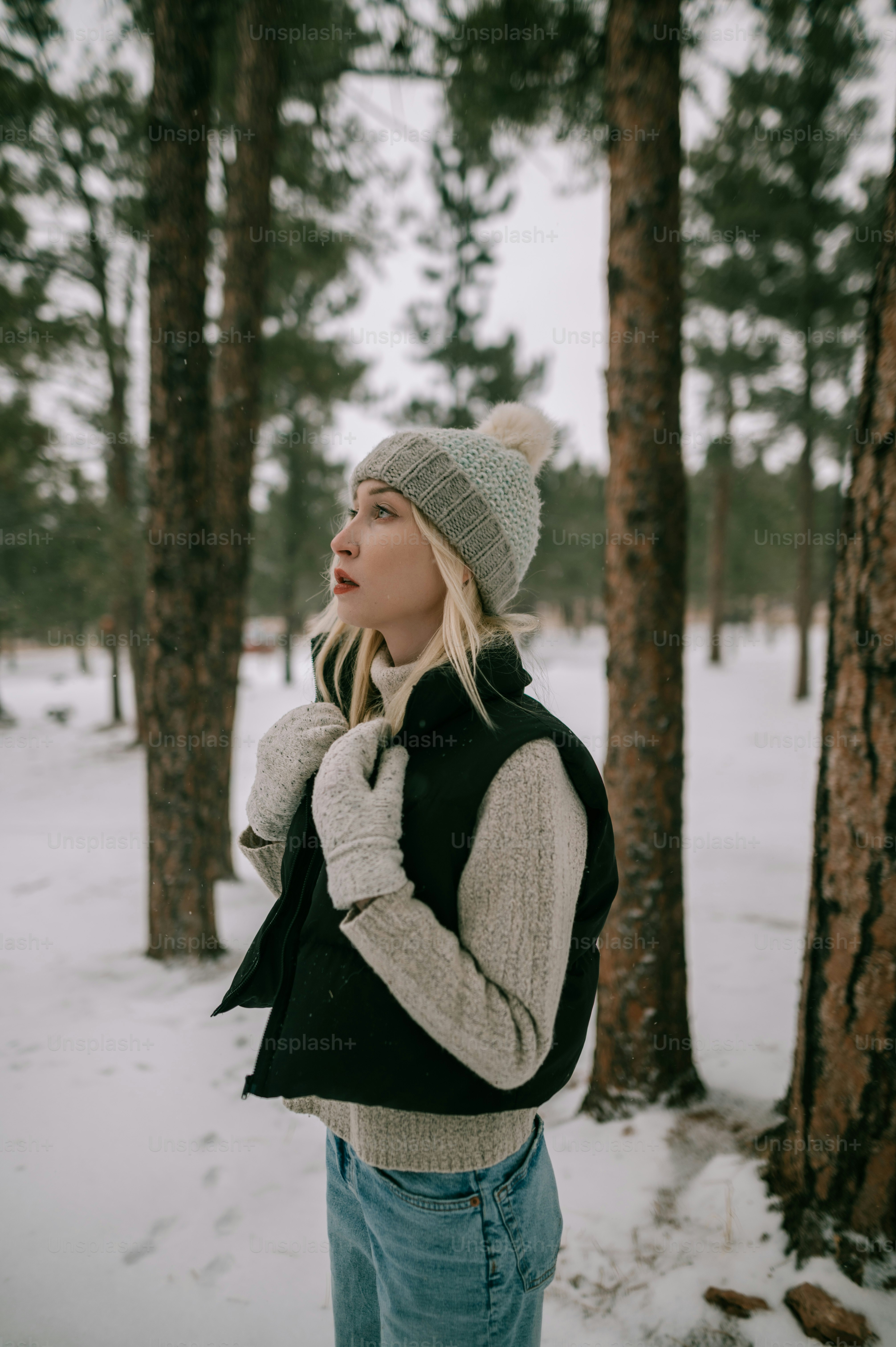 a woman standing in the snow in front of some trees
