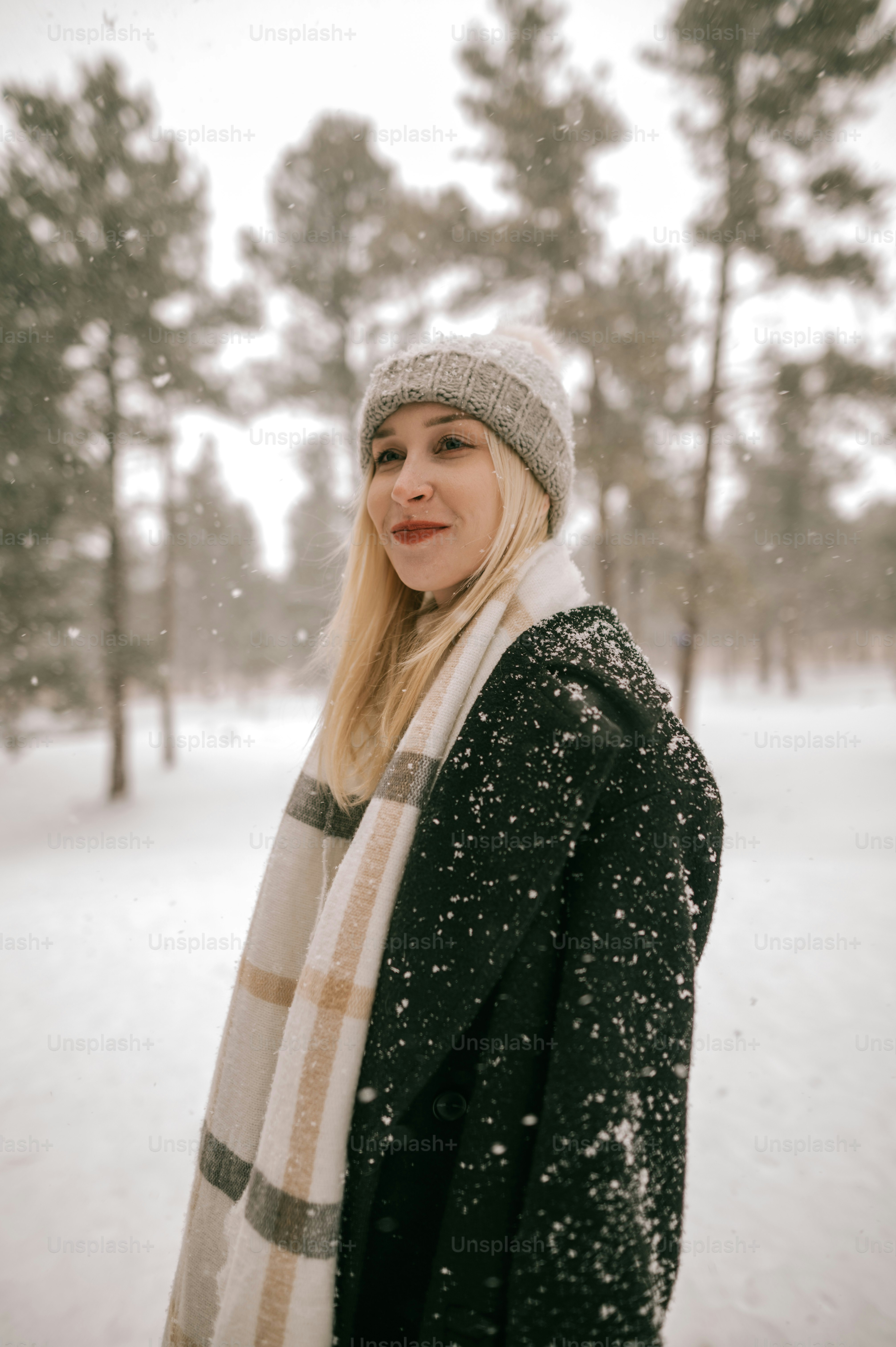 a woman standing in the snow wearing a hat and scarf