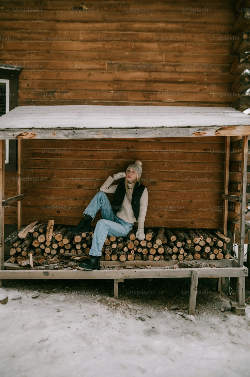 uma mulher sentada em cima de uma pilha de troncos