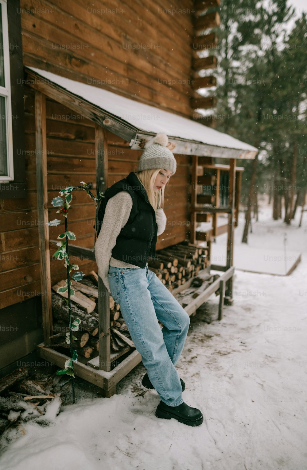 a woman standing outside of a cabin in the snow