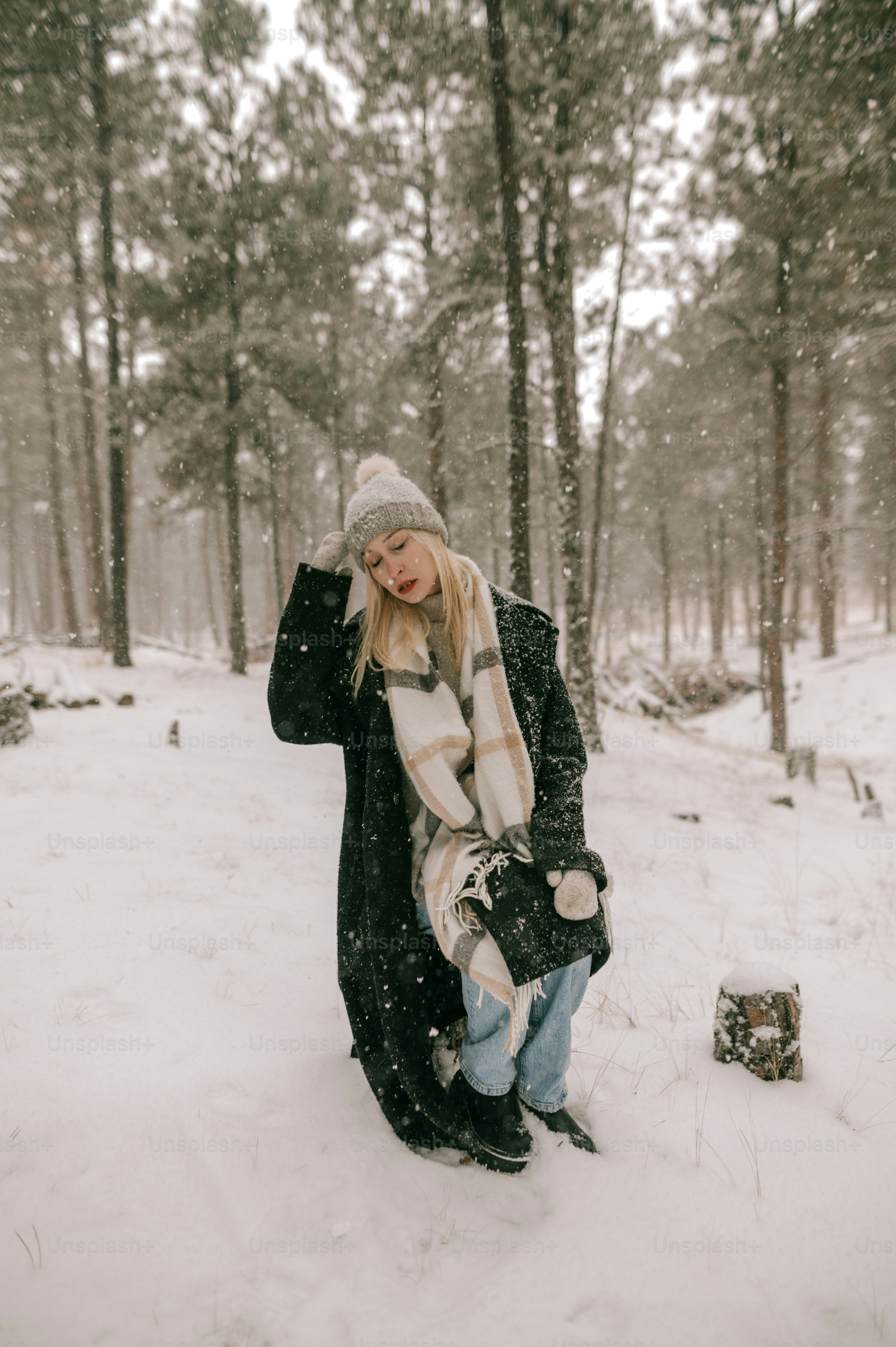 a woman is standing in the snow in the woods