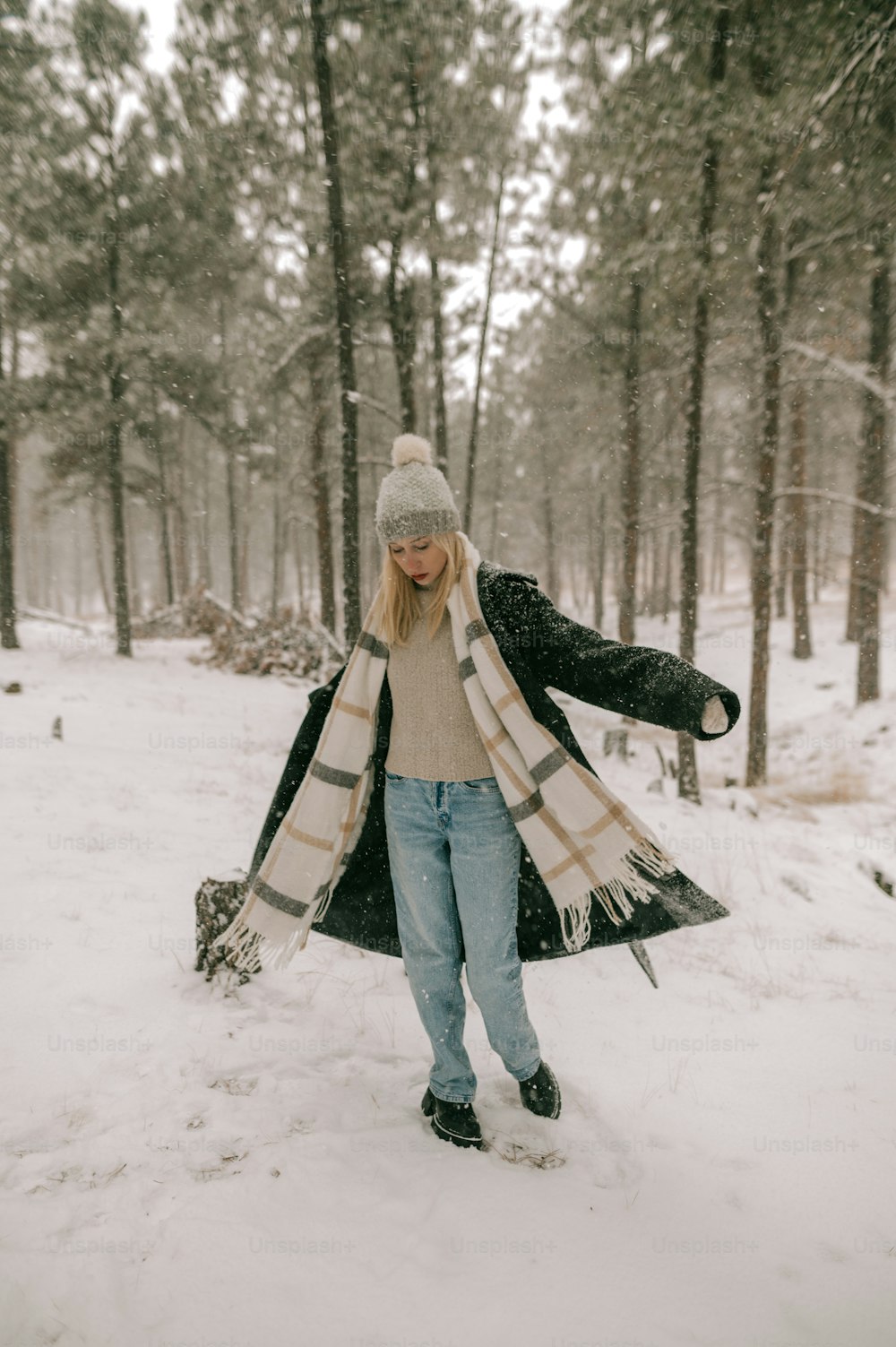 a woman is walking through the snow in the woods