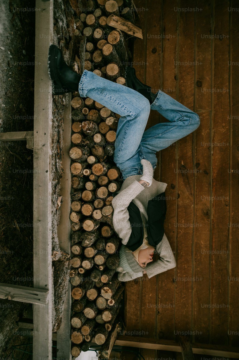 um homem deitado em cima de uma pilha de troncos