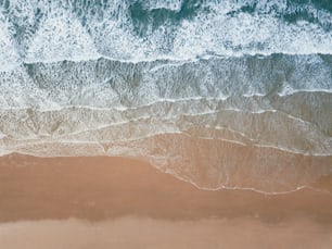 uma vista aérea de uma praia de areia com ondas