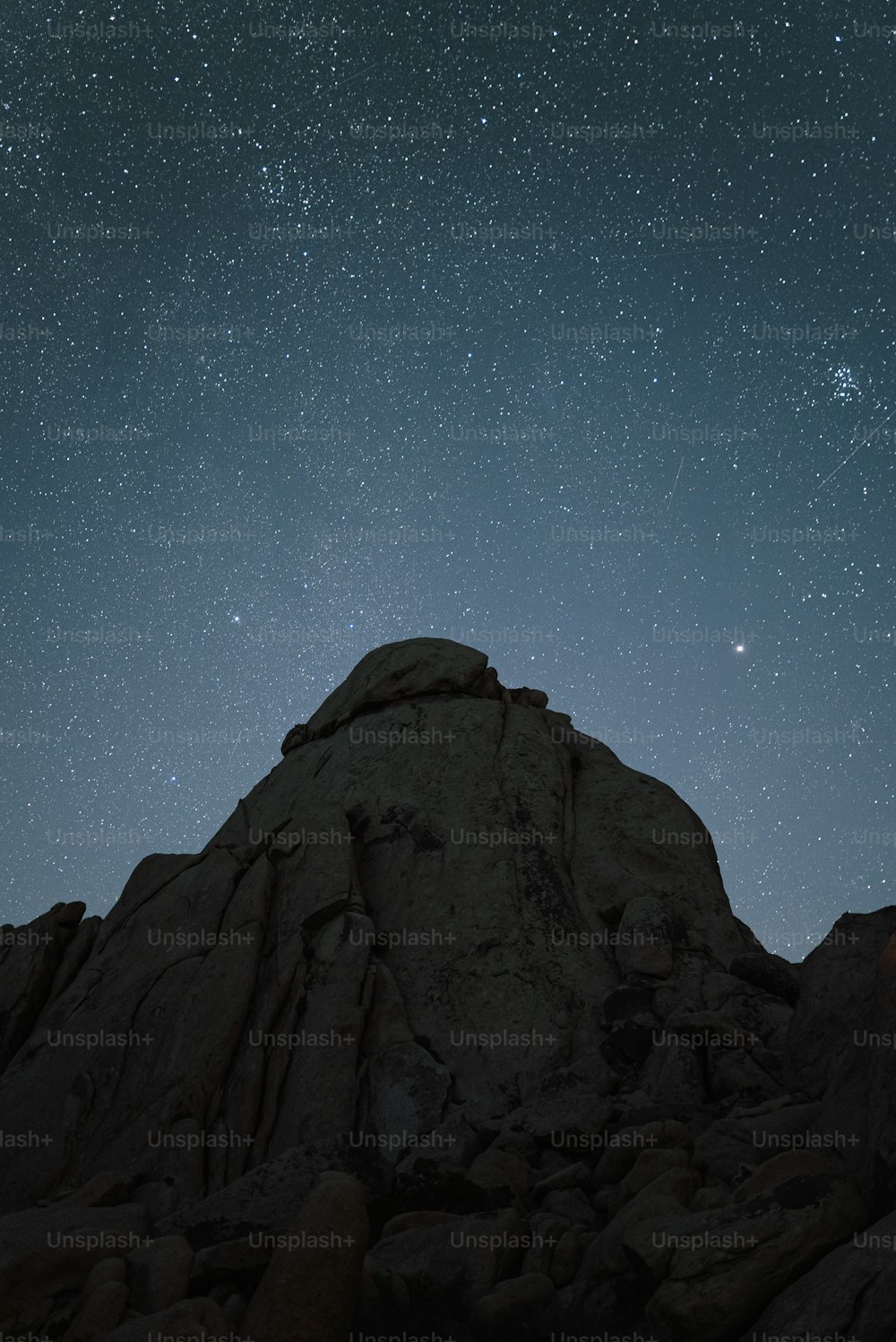 the night sky with stars above a rocky mountain