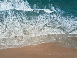 an aerial view of a sandy beach with waves