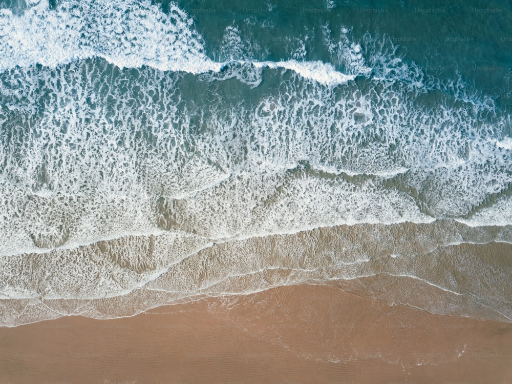 uma vista aérea de uma praia de areia com ondas