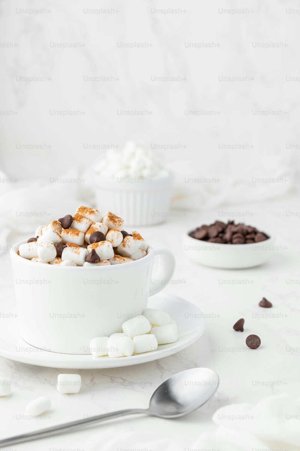 um copo branco cheio de marshmallows e lascas de chocolate