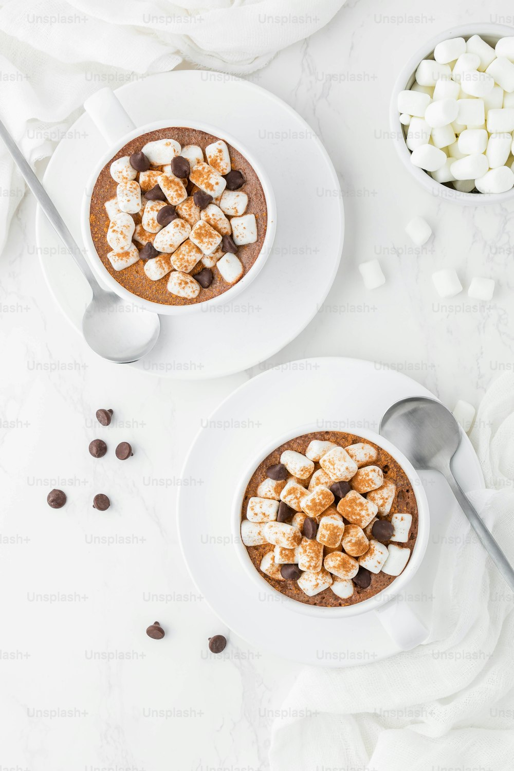 two bowls of hot chocolate with marshmallows and chocolate chips