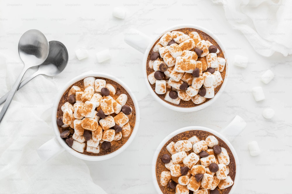 três canecas de chocolate quente e marshmallows