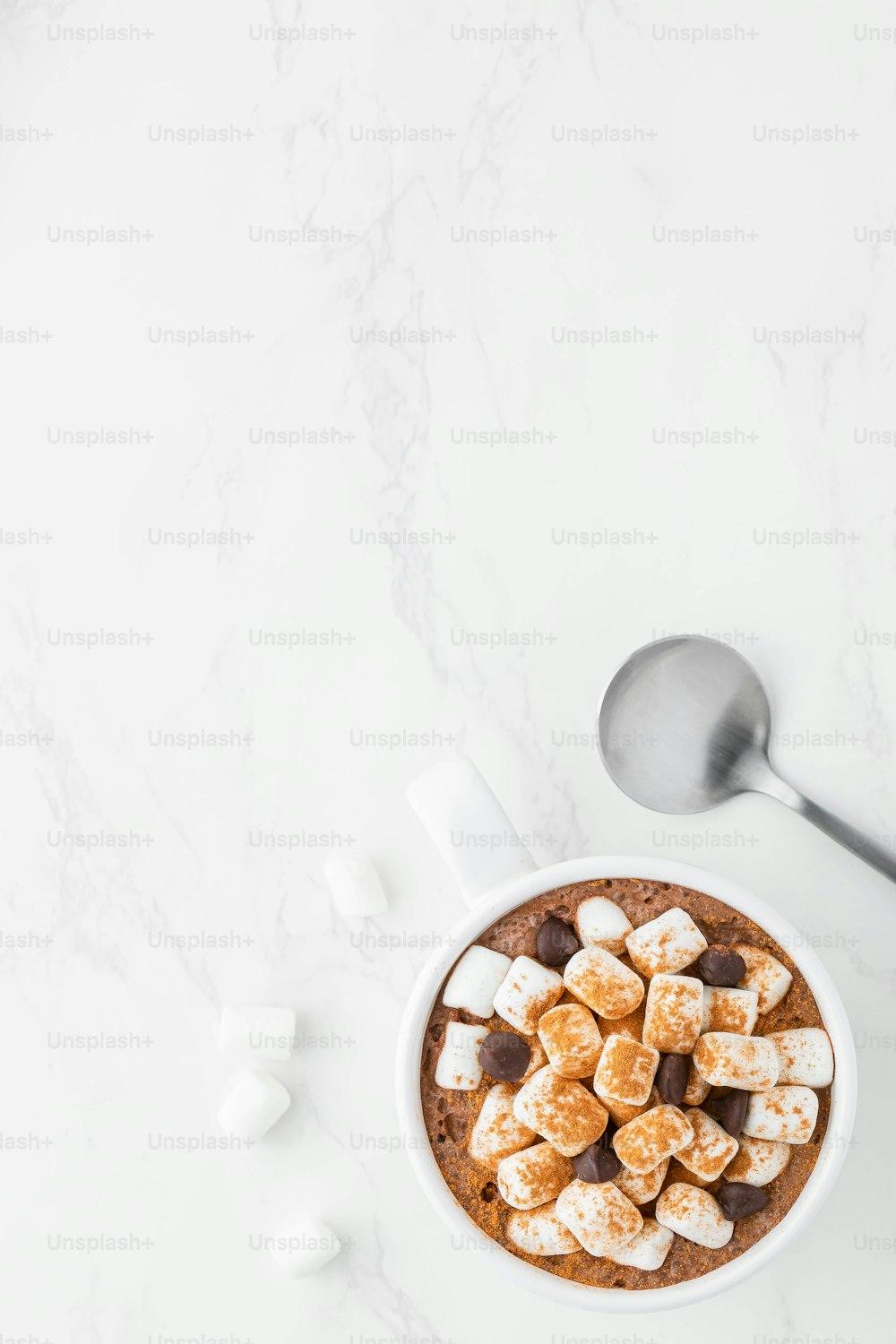 a bowl of hot chocolate with marshmallows and a spoon