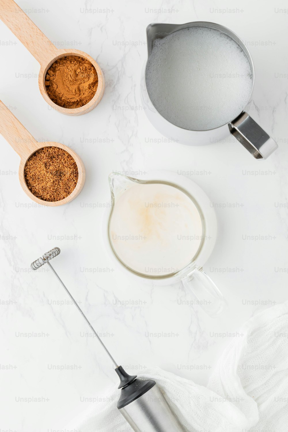 a whisk, a measuring cup, and a measuring spoon on a white