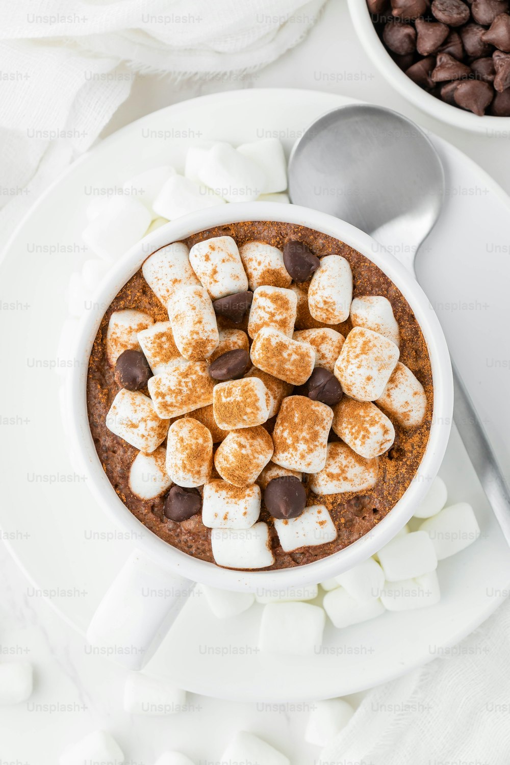 uma tigela de chocolate quente e marshmallows em um prato