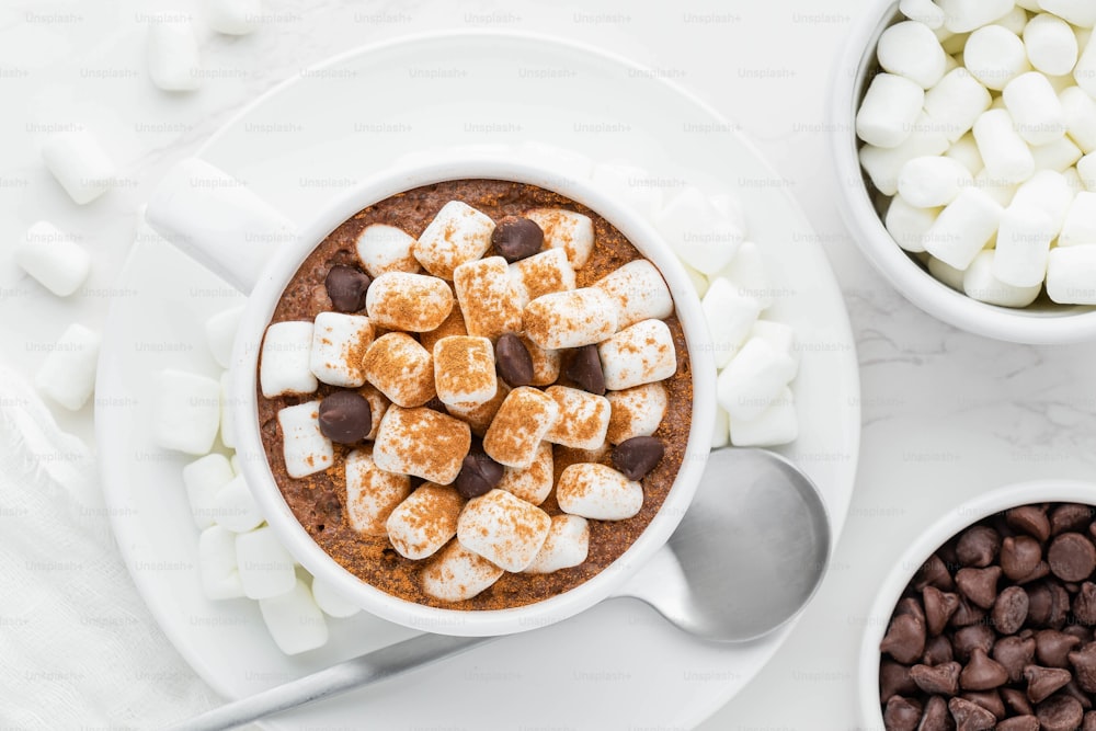 uma tigela de chocolate quente com marshmallows e lascas de chocolate