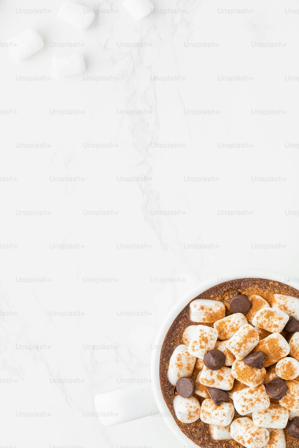 a cup of hot chocolate and marshmallows on a white table