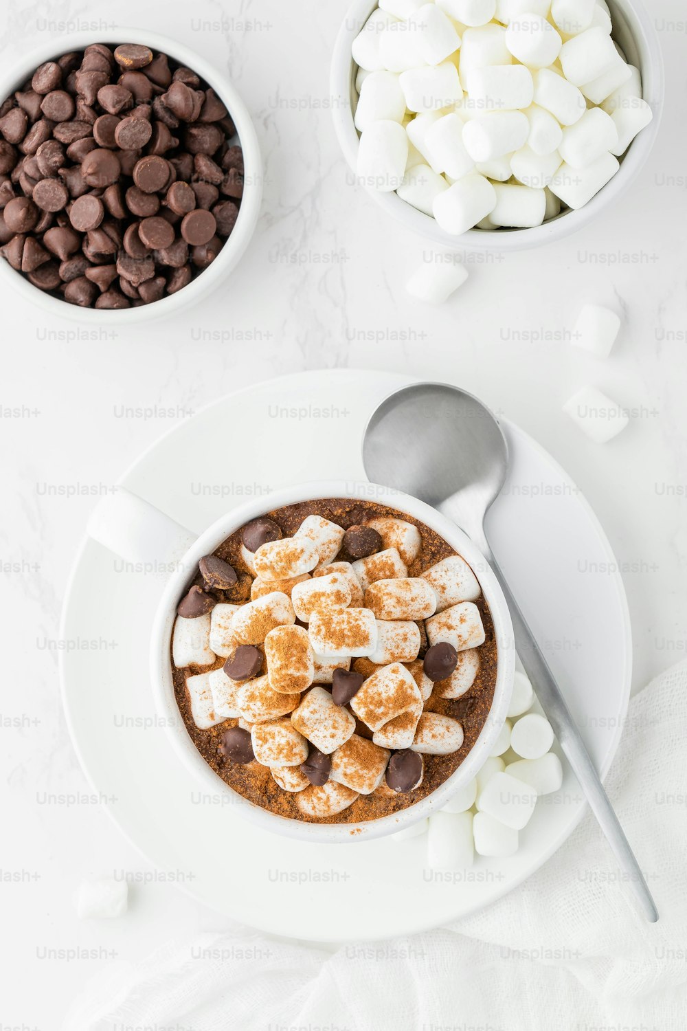 uma tigela de chocolate quente com marshmallows e uma colher