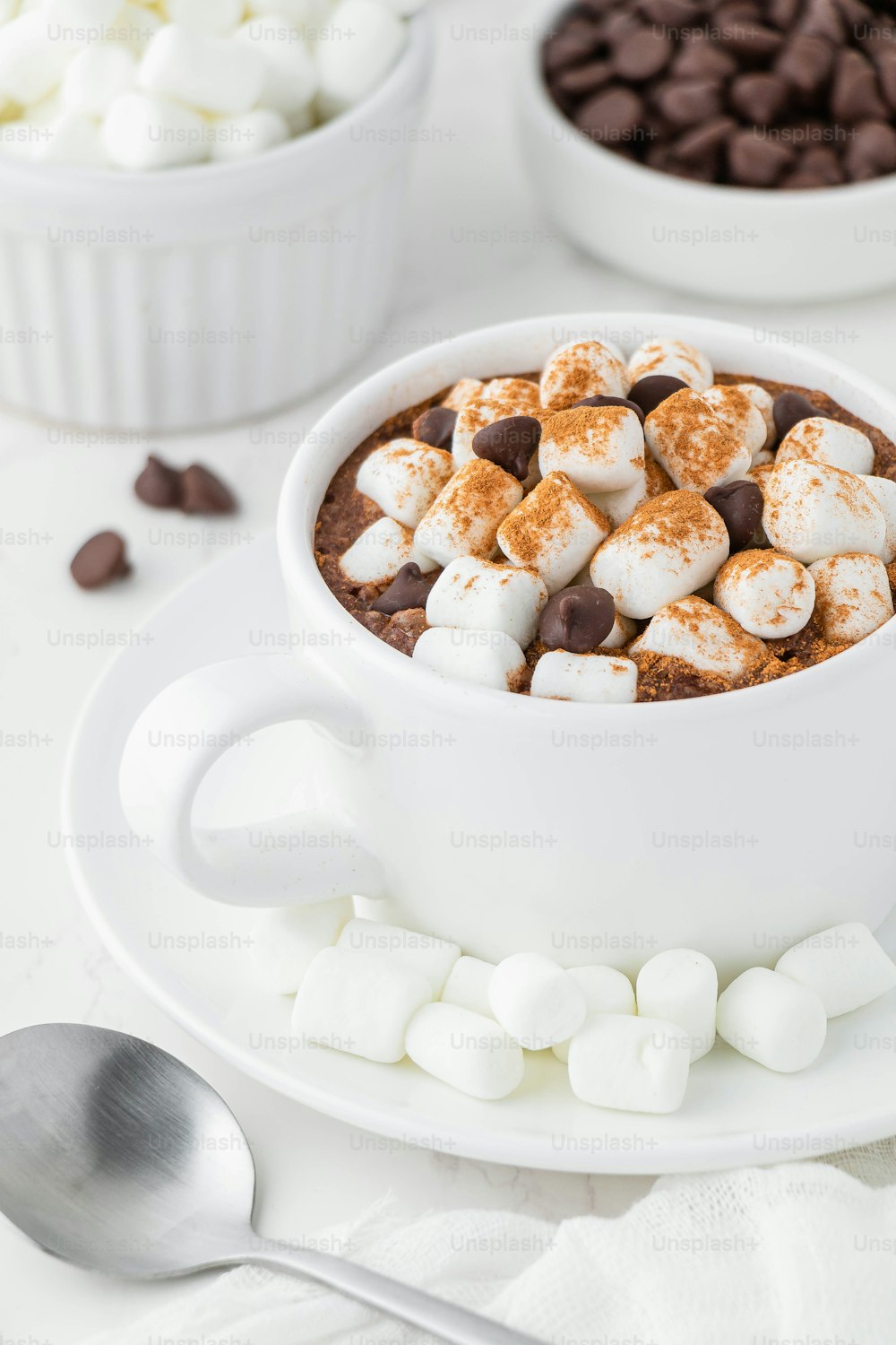 uma tigela de chocolate quente com marshmallows e lascas de chocolate