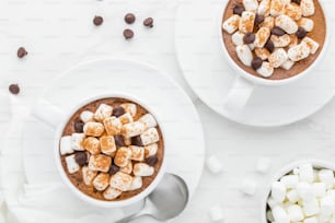 two cups of hot chocolate with marshmallows and chocolate chips