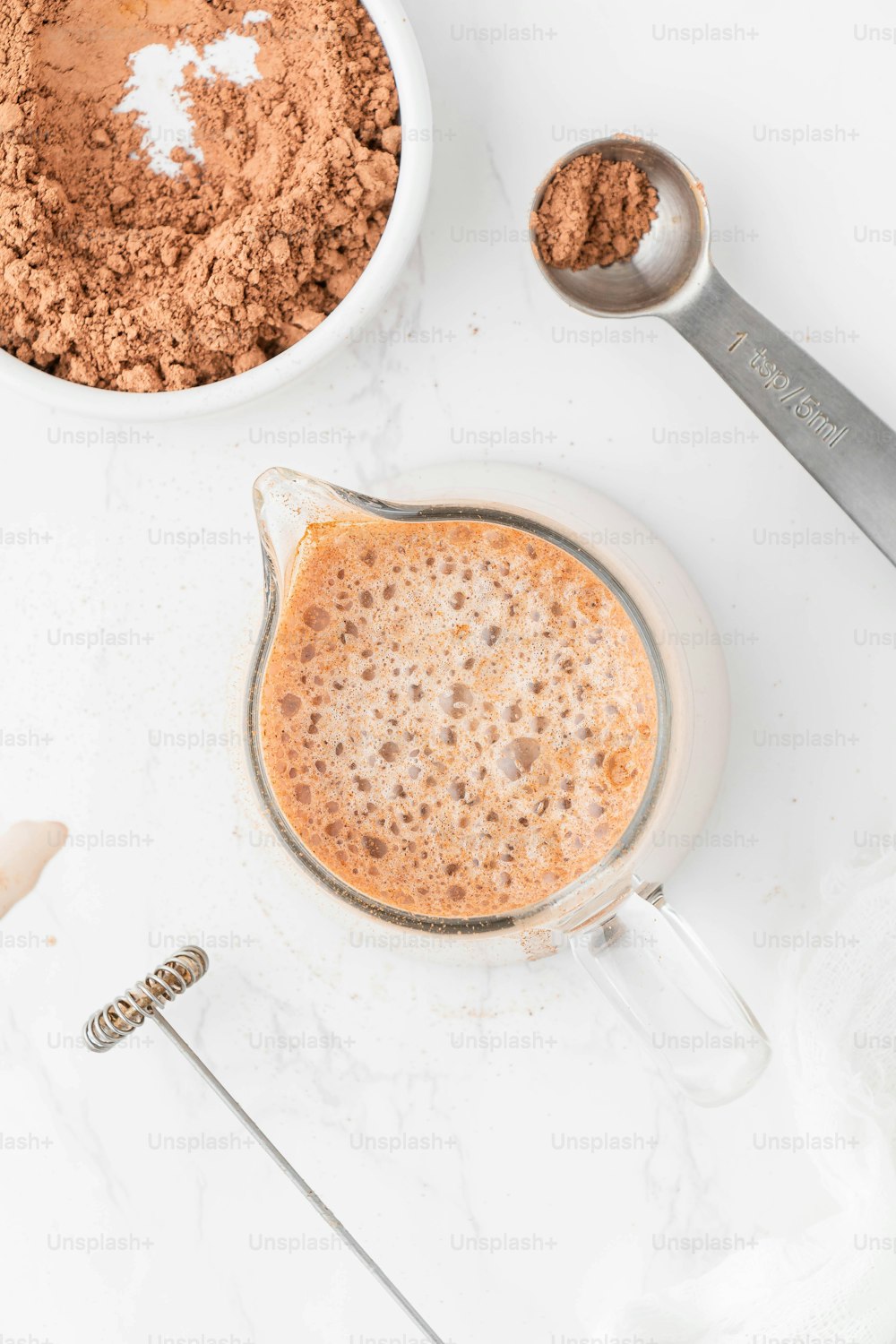 a bowl of cocoa next to a measuring spoon