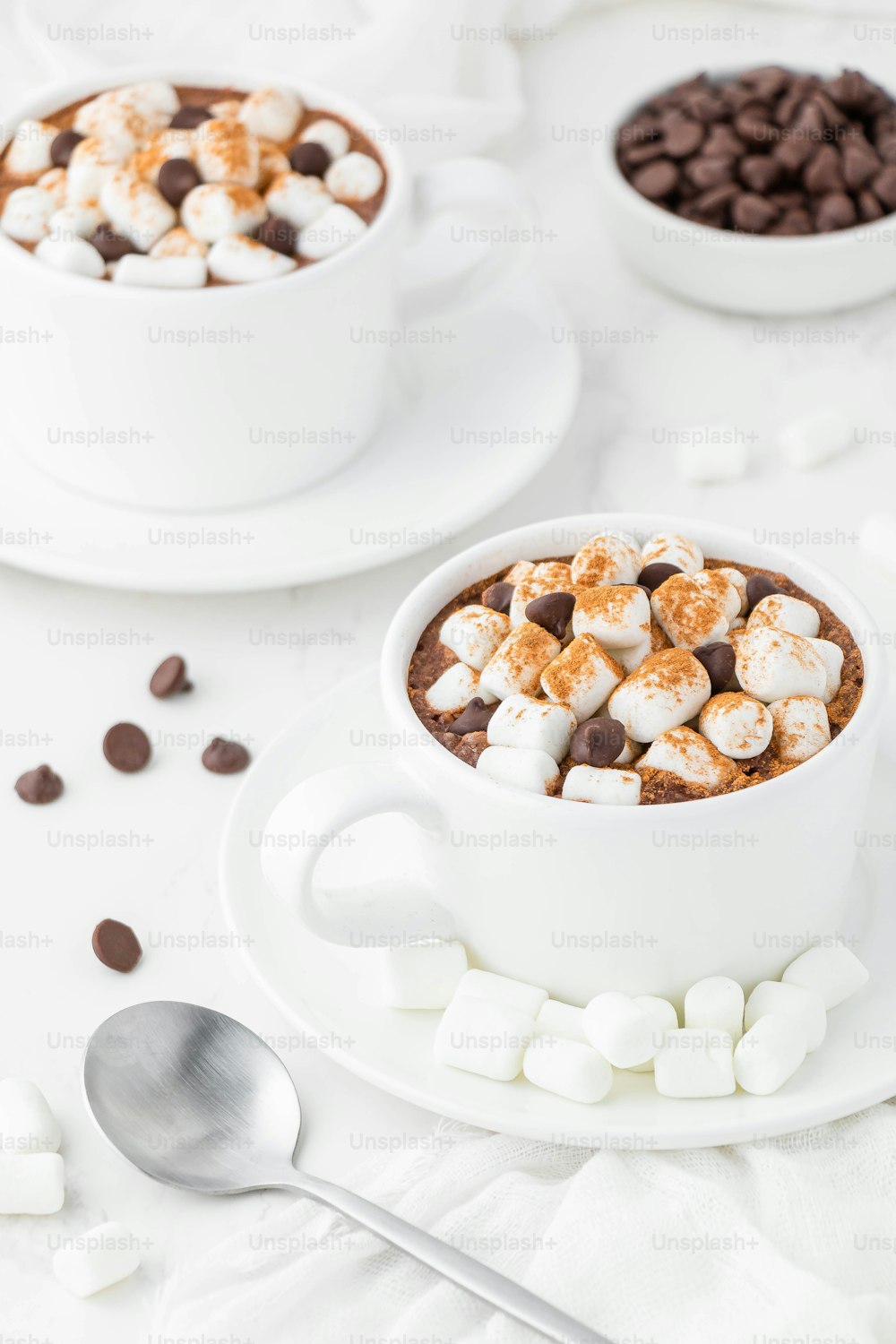 two cups of hot chocolate with marshmallows and chocolate chips