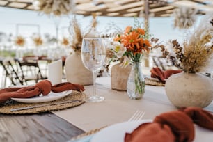 a table set with a vase of flowers and a glass of wine