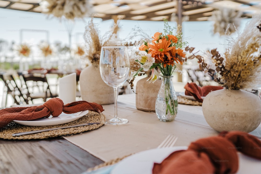 une table dressée avec un vase de fleurs et un verre de vin
