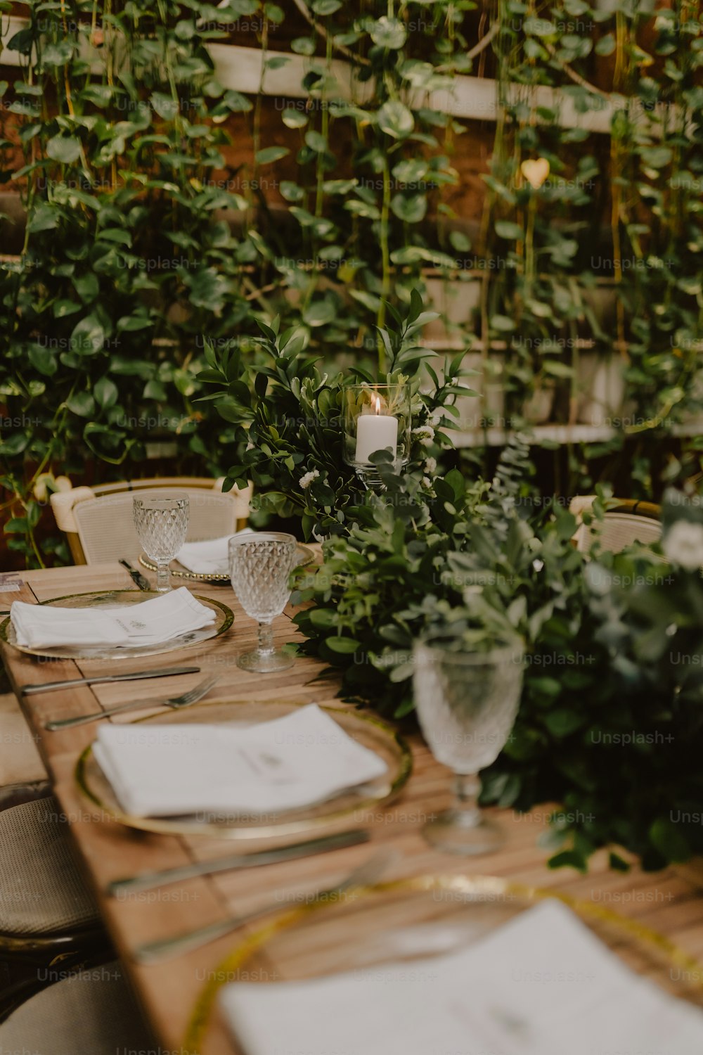 a table set with place settings and greenery