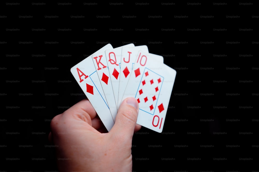a person holding four playing cards in their hand