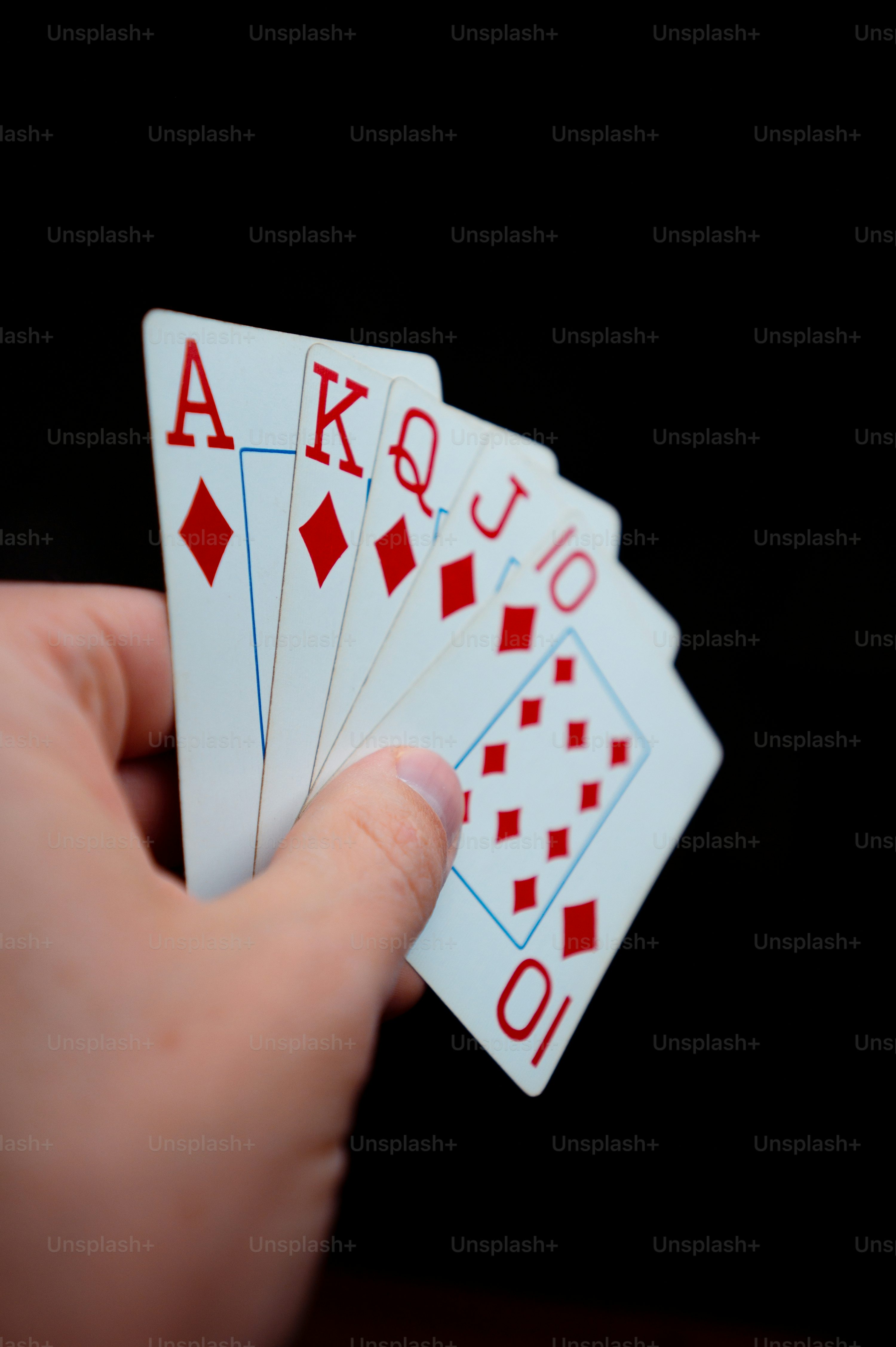 a person holding four playing cards in their hand