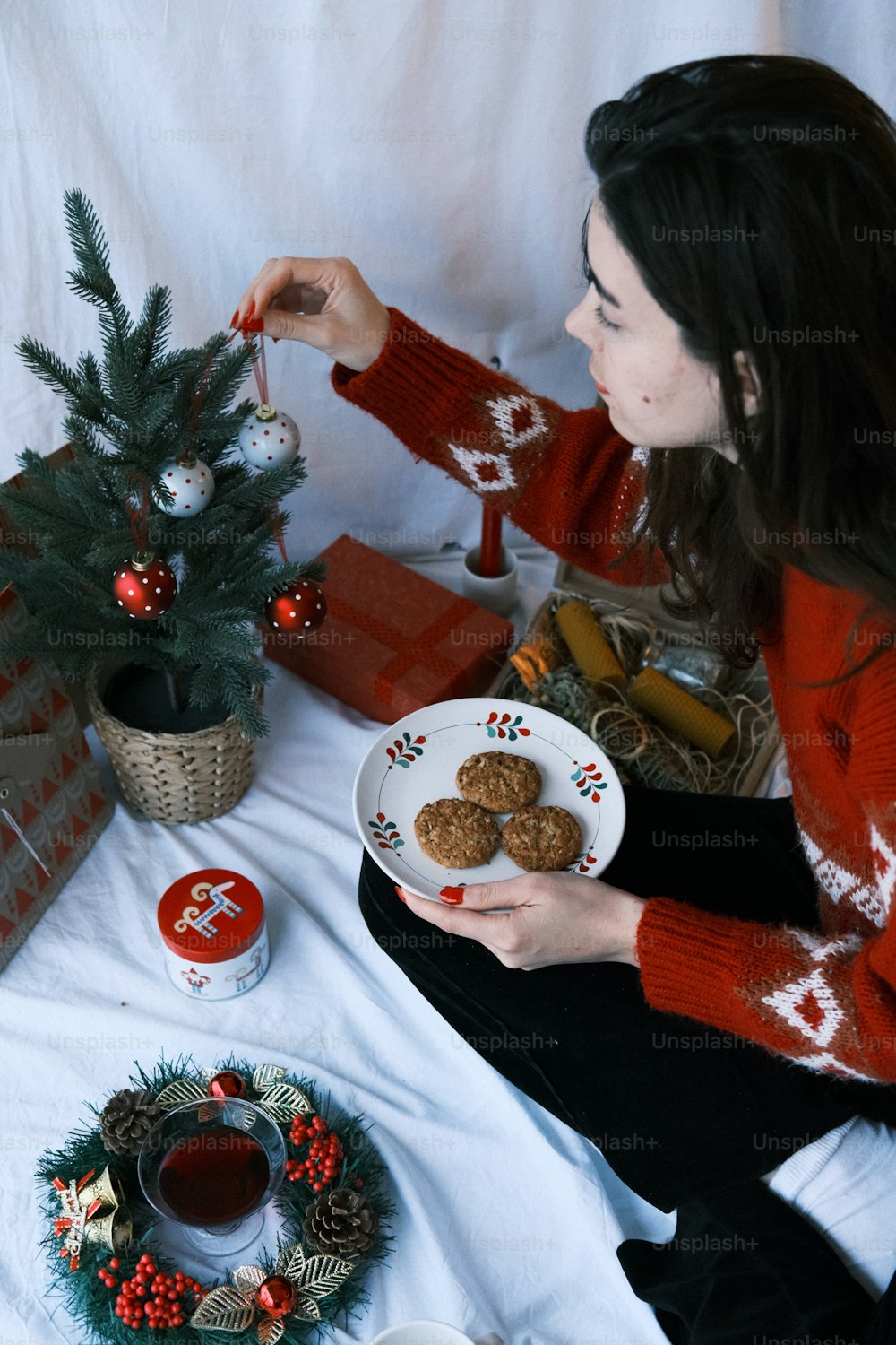 a woman sitting on a bed holding a plate of cookies