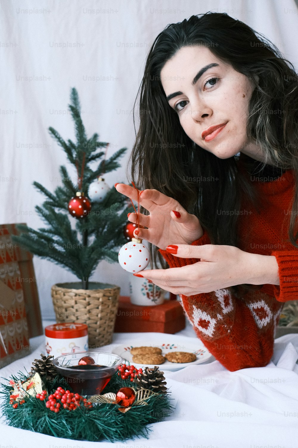 Une femme en pull rouge tenant un ornement de Noël