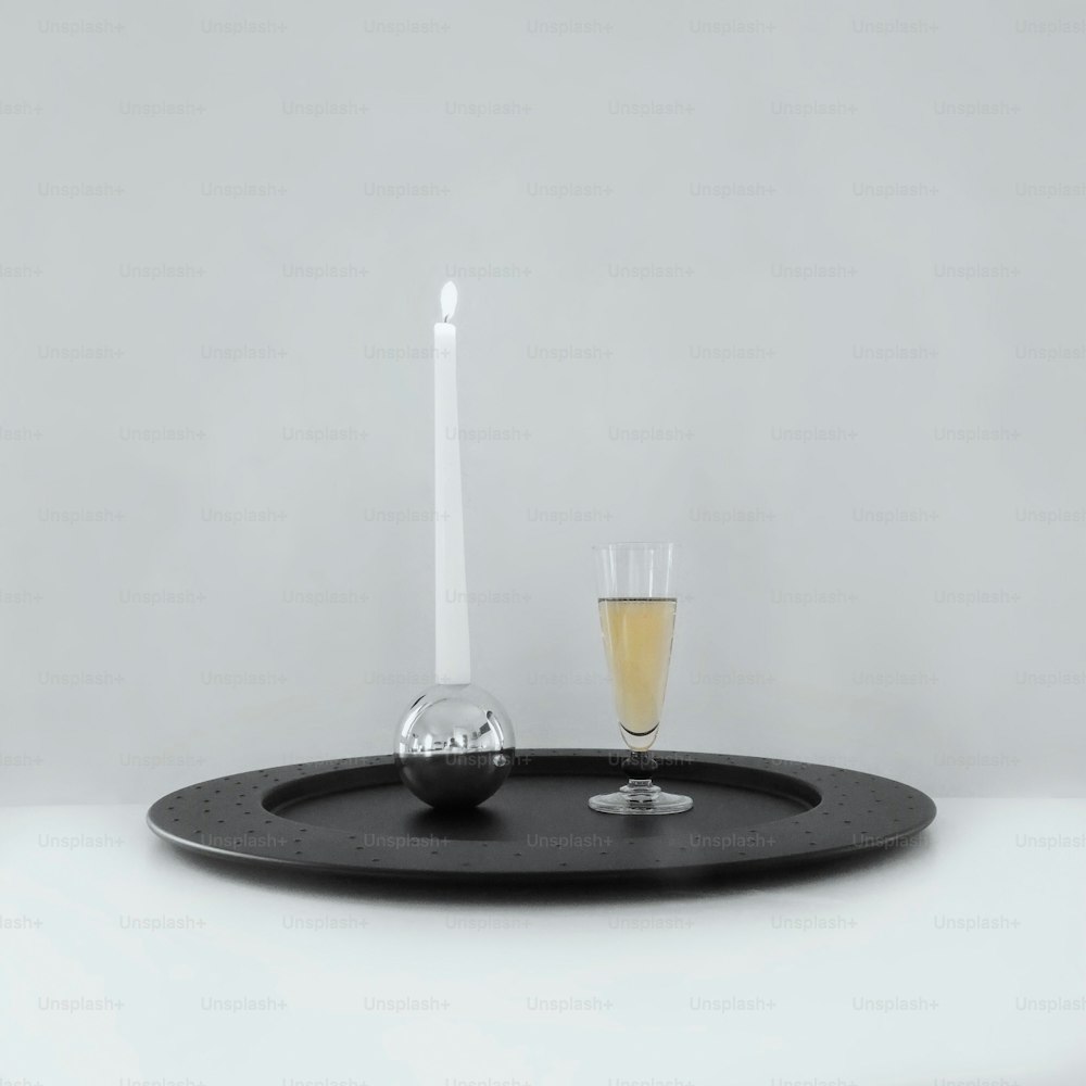 um copo de vinho e uma vela em uma bandeja