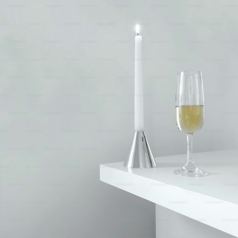 Una copa de vino junto a una vela sobre una mesa