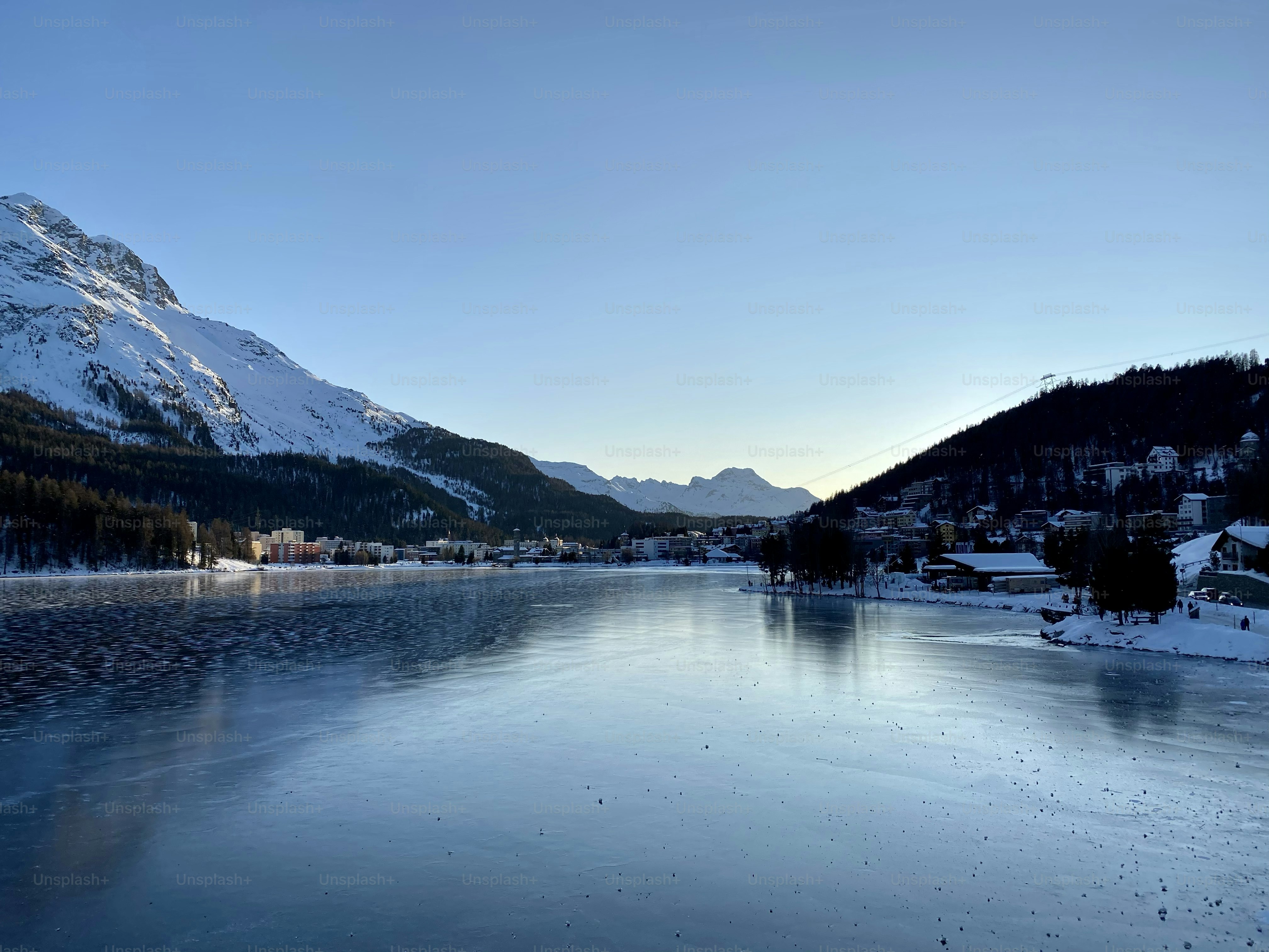 a body of water surrounded by snow covered mountains