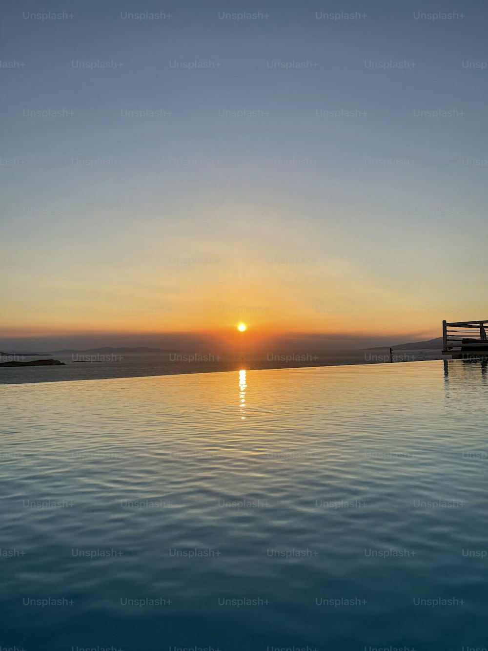 the sun is setting over the water of a swimming pool