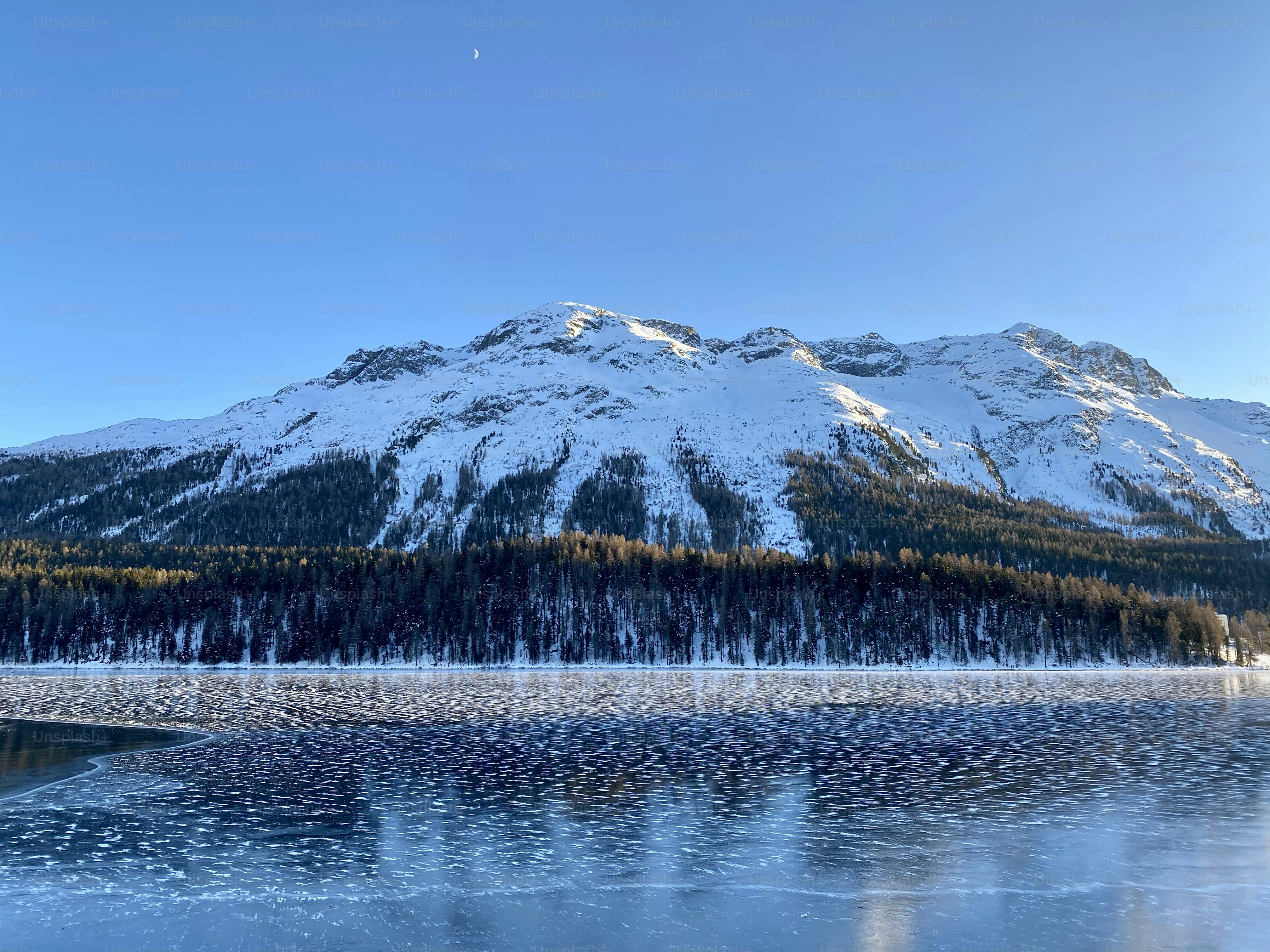 a mountain covered in snow next to a lake