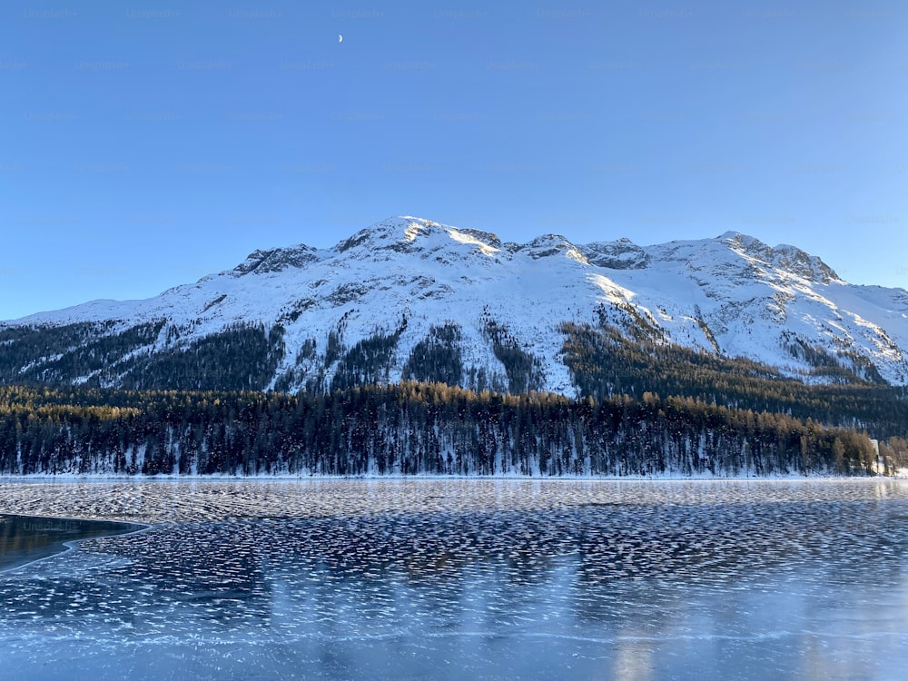 Ein schneebedeckter Berg neben einem See