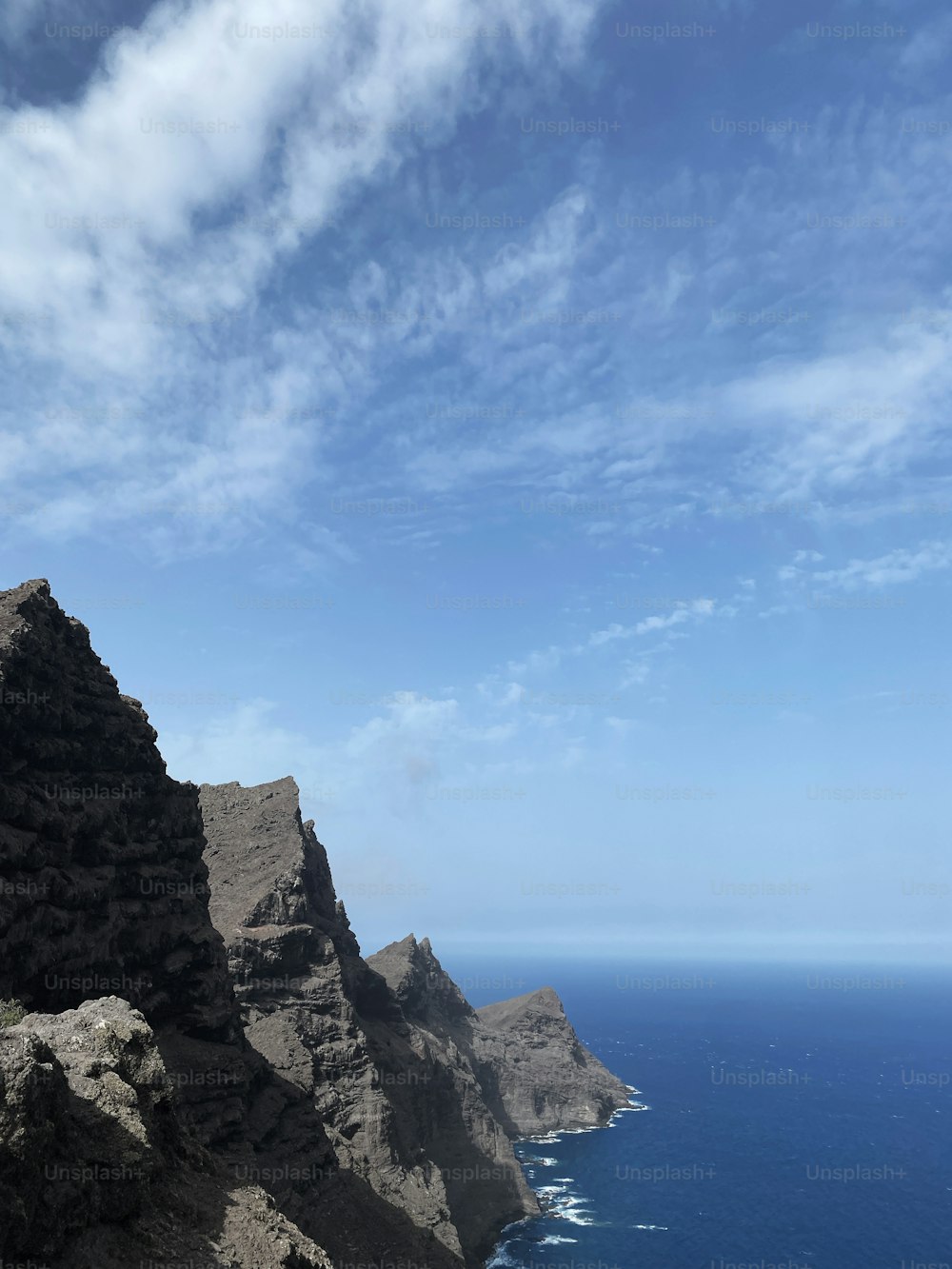 um homem de pé no topo de uma montanha ao lado do oceano