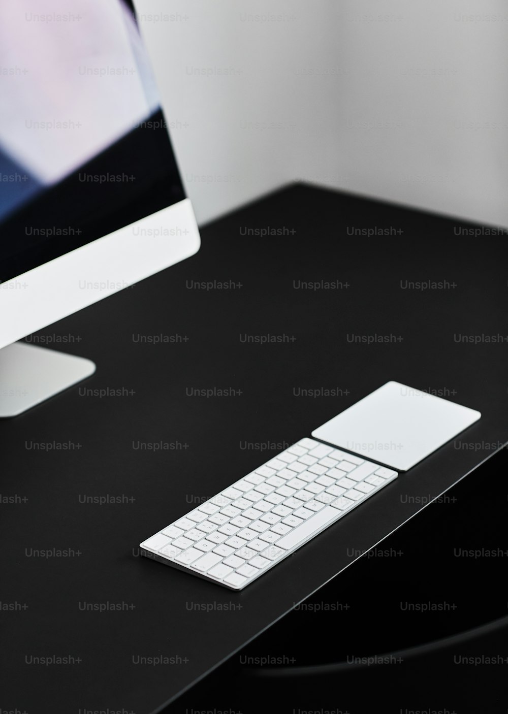 a black desk with a white keyboard and a monitor