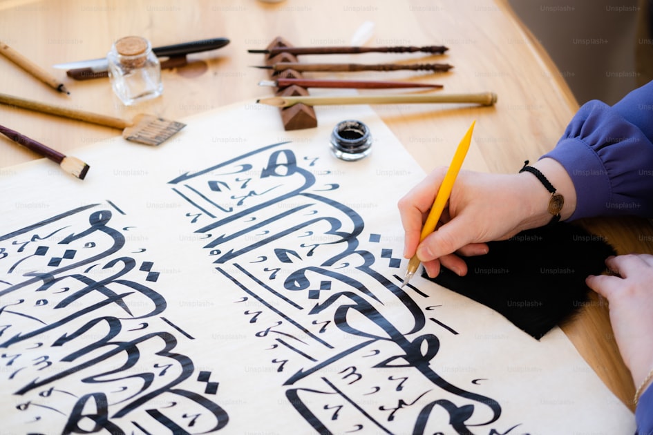 Persona che scrive a mano su un foglio con calligrafia elegante