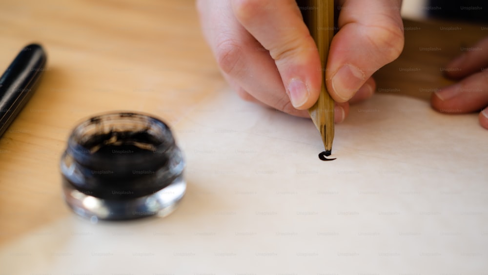 uma pessoa escrevendo em um pedaço de papel com uma caneta