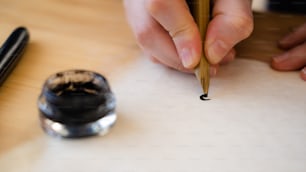 a person writing on a piece of paper with a pen